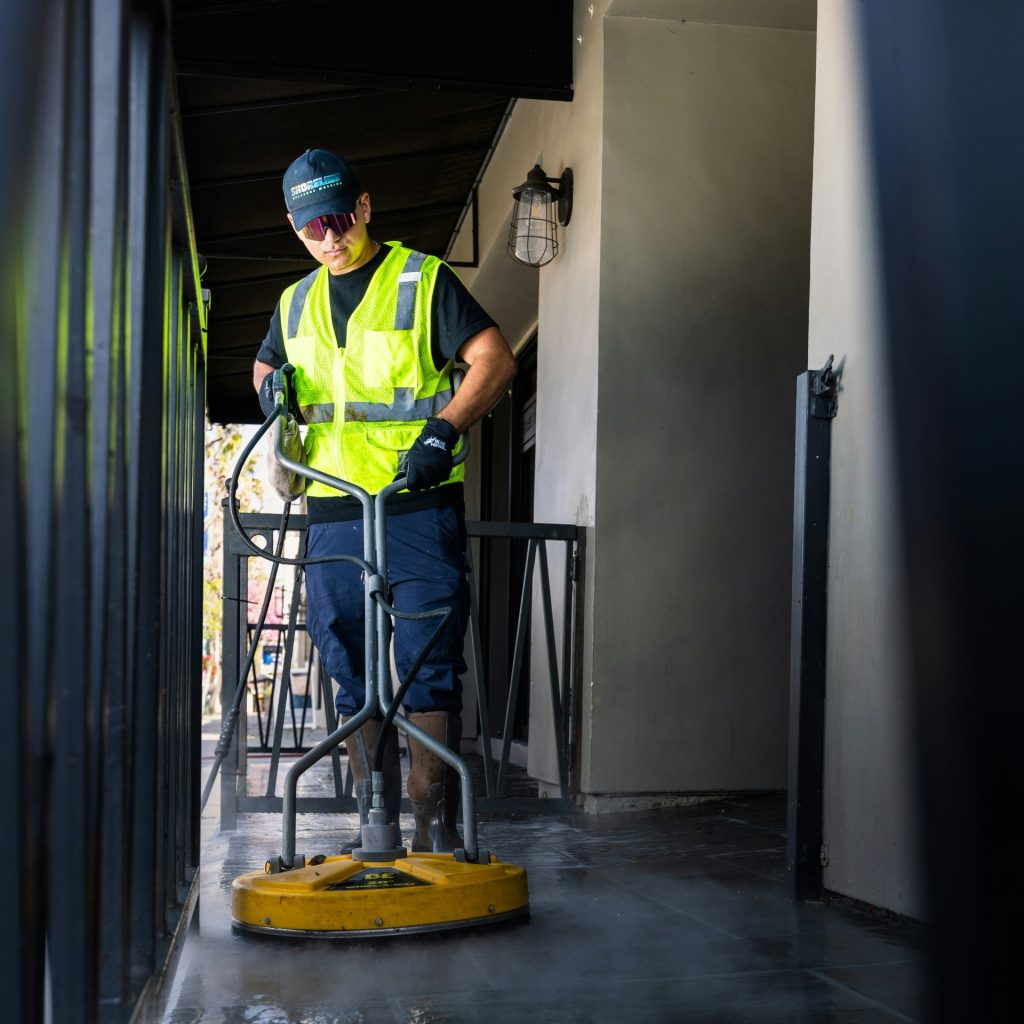 a man in a yellow vest is cleaning the floor
